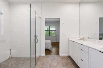 A bathroom with a shower and a sink and a bedroom